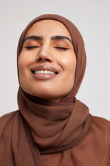 Studio portrait of smiling woman wearing brown hijab