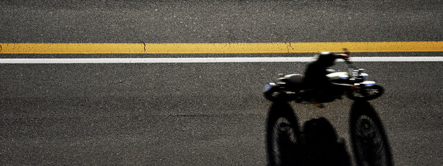 Horizontal banner with top view of the Biker driving his motorcycle on the asphalt road - Man is...