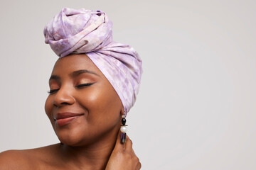 Studio shot of smiling woman in headscarf and ethnic earrings