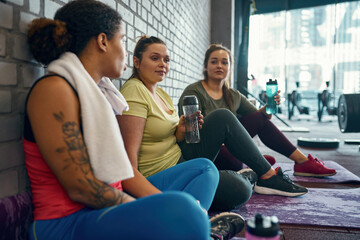 Girls rest and drink water after training in gym