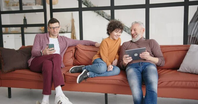 Happy gay LGBT family looks at funny photos on tablet laughing