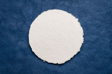 circular sheet of blank white watercolor paper against textured handmade bark paper