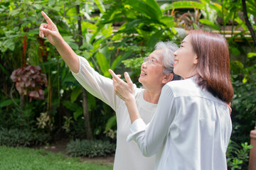 An old elderly Asian woman and walking in the backyard with her daughter.  Concept of happy retirement With care from a caregiver and Savings and senior health insurance, Happy family