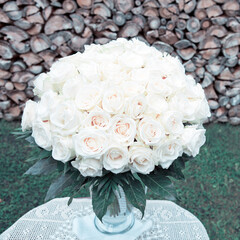 Bouquet of white roses in a glass vase on gray background.