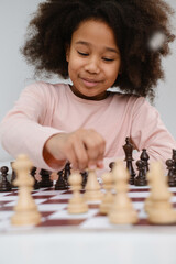 African American girl playing chess. Happy smiling child behind chess smiling in class or school...