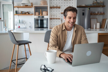 Smiling middle-aged man working remotely typing on a keyboard and answering emails.