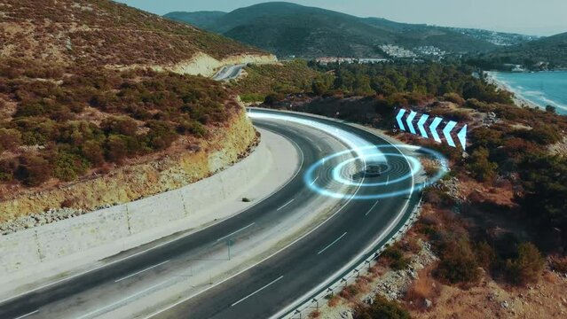 Road control system warns of a dangerous turn. Autonomous self-driving car moving along a beautiful mountain highway. Artificial intelligence scans and analyzes the road using GPS sensors, aerial view