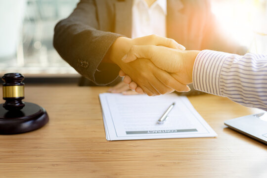 Lawyer and client shake hands, after winning a lawsuit where a lawyer hired by a client in a fraud case and proceeding in a fair and correct manner, the client wins the case. Fraud litigation concept.