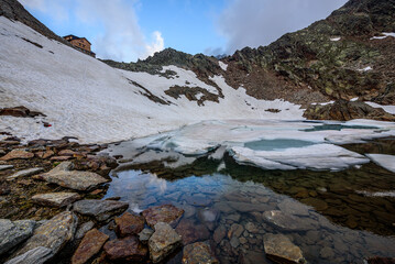 A little frozen lake below Hildesheimer Hütte - a mountain hut under the Zuckerhutl mountain in austrian Stubai Alps.