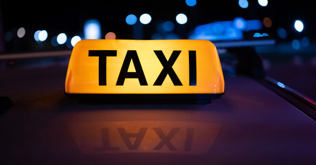 Taxi car light on dark street at night with illumination. Cab sign on the vehicle roof closeup...