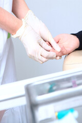 A child gives blood from a finger in a medical laboratory. Blood test. A nurse and a child. The concept of healthcare.Unrecognizable persons.Vertical photo.