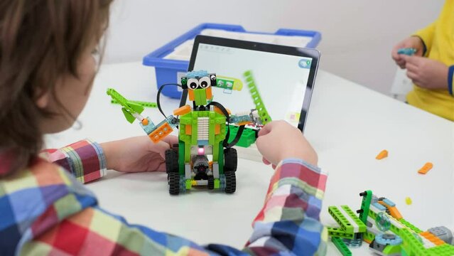 Students In School Computer Coding Class Building And Learning To Program Robot Vehicle. Multi ethnic children making science, technology and coding tasks at school with tablet. Modern education