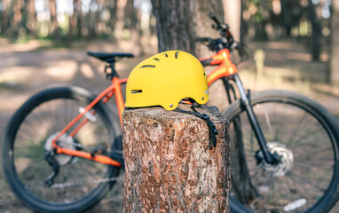 Yellow Bicycle helmet on stump and bike in pine forest