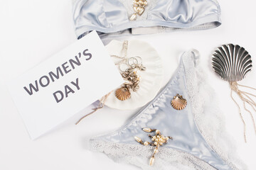 Obraz na płótnie Canvas Top view of card with womens day lettering near accessories and silk lingerie on white background