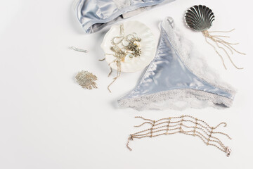 Obraz na płótnie Canvas Top view of accessories near blue silk lingerie on white background