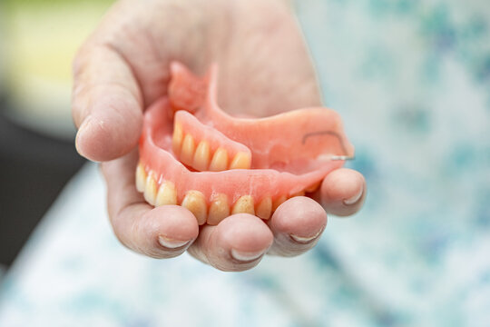Asian senior or elderly old woman patient holding to use denture in nursing hospital ward, healthy strong medical concept