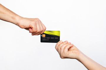 The black plastic credit card is in the hands of two women holding it from different sides isolated on a white background. Shopping, payment for purchases, banking operations. Close up