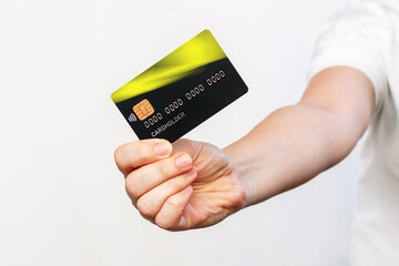 Cropped shot of a young woman in a white t-shirt holding a black plastic credit card in her hand isolated on a white background. Shopping, payment for purchases, banking operations. Close up