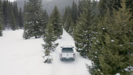 Aerial drone of a pickup truck car driving on a snowy mountain road forest during winter, panoramic view - Powered by Adobe