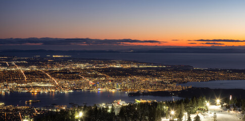 View of Top of Grouse Mountain Ski Resort with the City in the background. North Vancouver, British Columbia, Canada. Sunset Sky