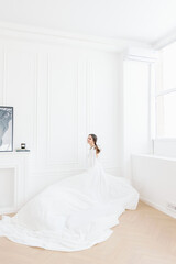 Fototapeta na wymiar A woman bride in a white airy white dress with a wavy train. Bright emotions and real joy and delight.