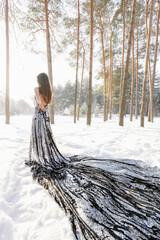 woman in a black silver dress with sequins and sequins against a winter snowy forest