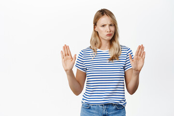 Portrait of woman showing stop sign, raising hands up, prohibit action, rejecting smth with angry...