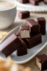 Chocolate candies with marshmallow filling on bright backgroundserved with cup of coffee