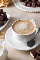 Cup of coffe with milk or cappuccino and chocolate candies, morning coffe