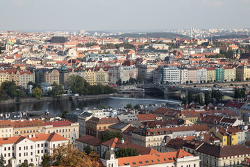 Fototapeta na wymiar Prague cityscape panoramic beautiful aerial view above the rooftops. Prague city center, view at river Vltava and rooftop buildings in the capital city of Czech Republic.