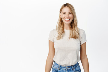 Portrait of happy smiling woman showing white smile, laughing and looking carefree at camera, standing over white background - 485865788