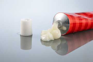 ointment for external use is slightly squeezed out of the tube next to the cap on a gradient background with reflection