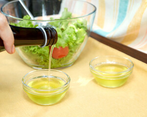 Salad preparation with vegetable oil. Vegetable oil is poured into small bowls. Shallow depth of field. Healthy food concept