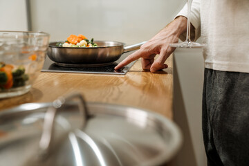 Obraz na płótnie Canvas European man making dinner with vegetables in kitchen