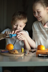a boy and his sister are doing electrical experiments with a soldering iron