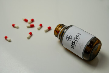 Bottle of pills with some of them out. A close up shot of an open pillbox against covid-19 on the table.