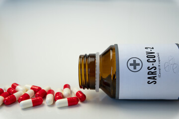 Bottle of pills with some of them out. A close up shot of an open pillbox against covid-19 on the table.