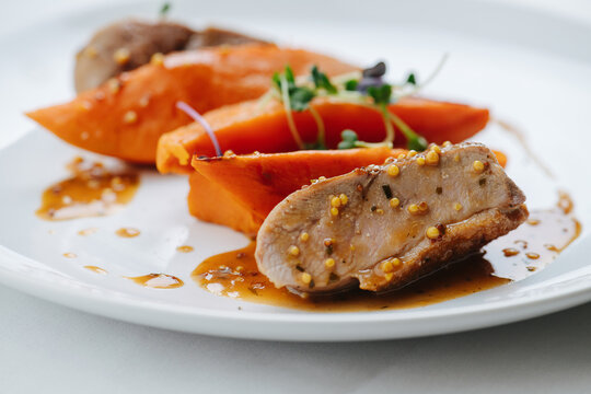 Close up image of plated chicken breast with carrot and sauce. Mustard balls and thyme on meat and vegetables.