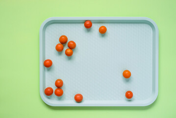 Top view of whole cherry tomatoes on a tray on green background