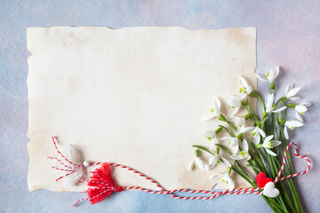 A bouquet of spring flowers of snowdrops and a red-white cord with tassels and hearts, martenitsa symbol, paper for congratulations text on a colorful background. Postcard for the holiday in March 1. - 485868794