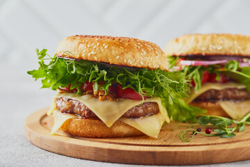 Two burgers with veal cutlet and herbs on wooden cutting board