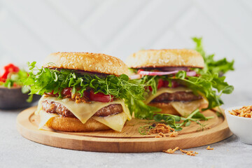 Two burgers with veal cutlet and herbs on wooden cutting board