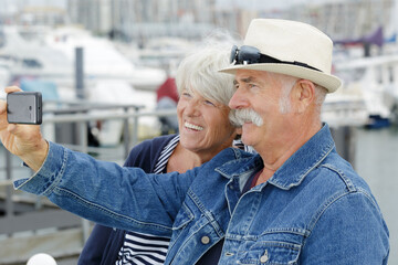 senior couple taking selfie with the marina in background