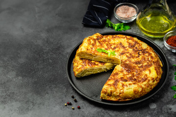 Spanish tortilla in cast iron skillet, dark background. Space for text.