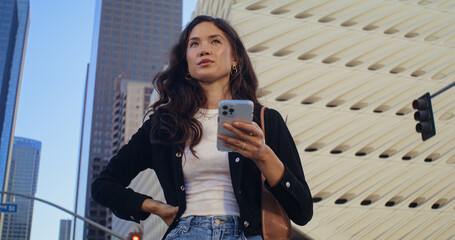 Beautiful girl using smartphone on street. Asian woman typing on phone closeup.