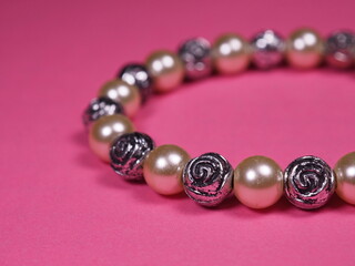 Bracelet with pearls on a pink background. Womens jewelry. Closeup of shiny hand bracelet