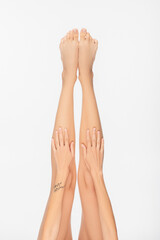 partial view of young woman with tattooed arm and slender legs isolated on white