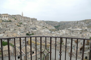 Pascoli viewpoint in Matera on the old city with the Cathedral bell tower on the top of the hill in the background, behind the iron railing of a balcony