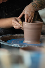 Fototapeta na wymiar Hands forming a piece of clay into a pot on a pottery wheel