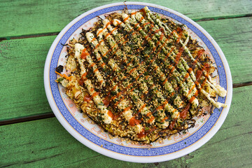 Freshly made Japanese okonomiyaki on a green table
